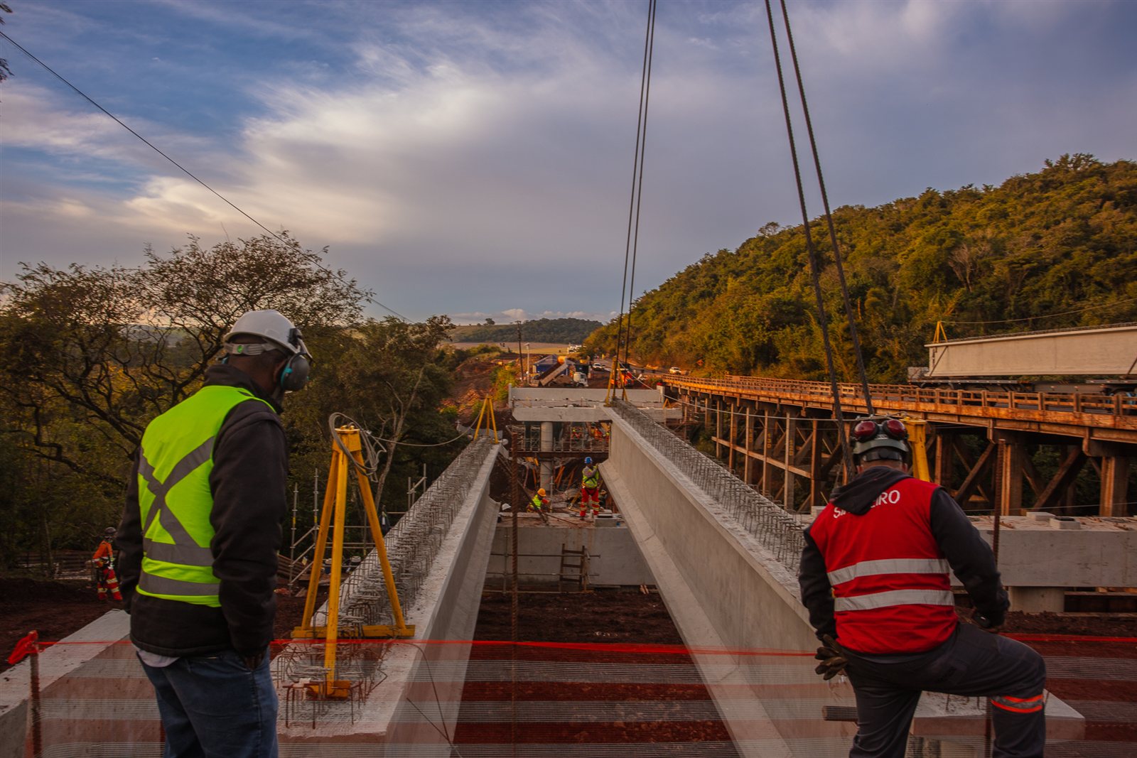 Equipe de obra acompanha o lançamento de vigas pré-moldadas para nova estrutura, ao lado da antiga ponte de treliça, em trecho da concessão EPR Litoral Pioneiro
