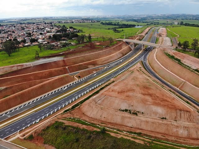 Vista aérea de trecho em obras do corredor Dom Pedro I, com terraplenagem e área urbana ao fundo