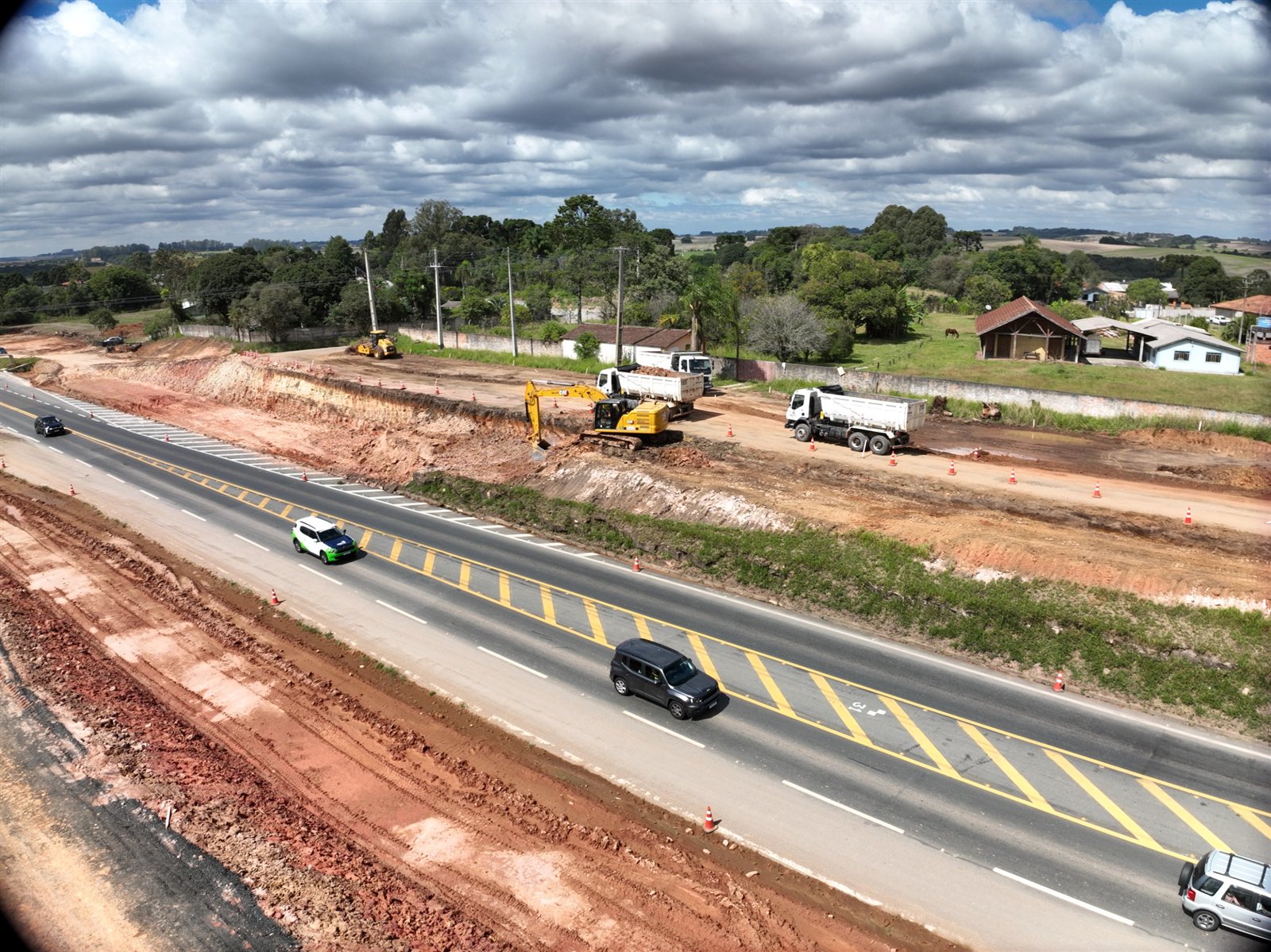 Escavadeira, caminhões e equipe em obra de duplicação da BR-277, entre Palmeira e Irati, no Paraná