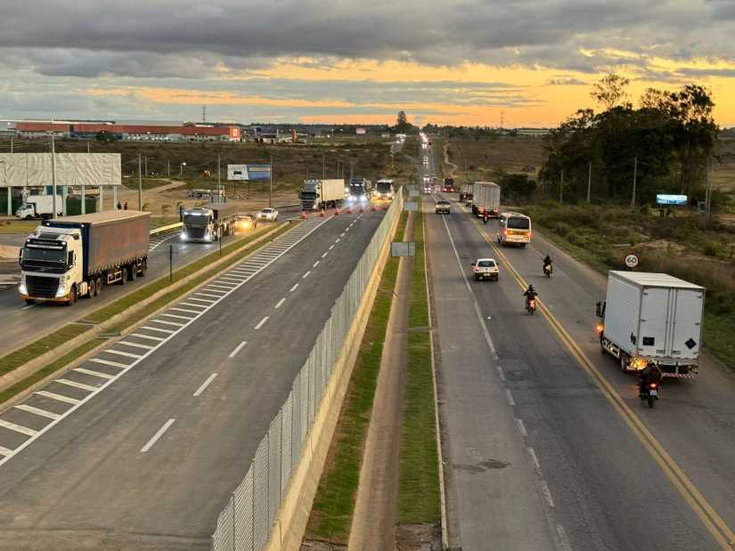 Vista da BR-116 duplicada ao entardecer em Vitória da Conquista, com tráfego de caminhões nas novas faixas