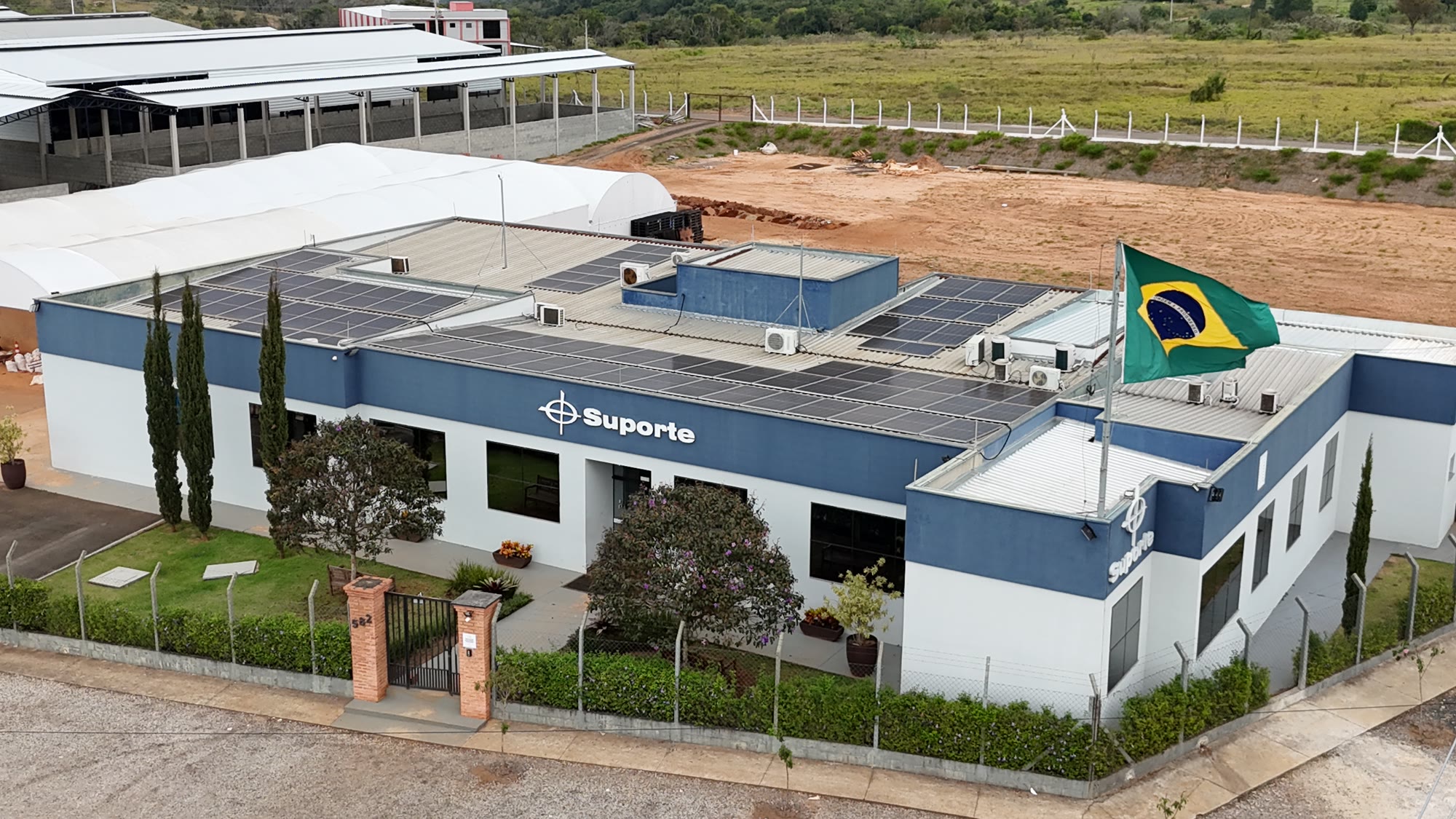 Vista aérea da sede da Suporte com painéis solares e bandeira do Brasil